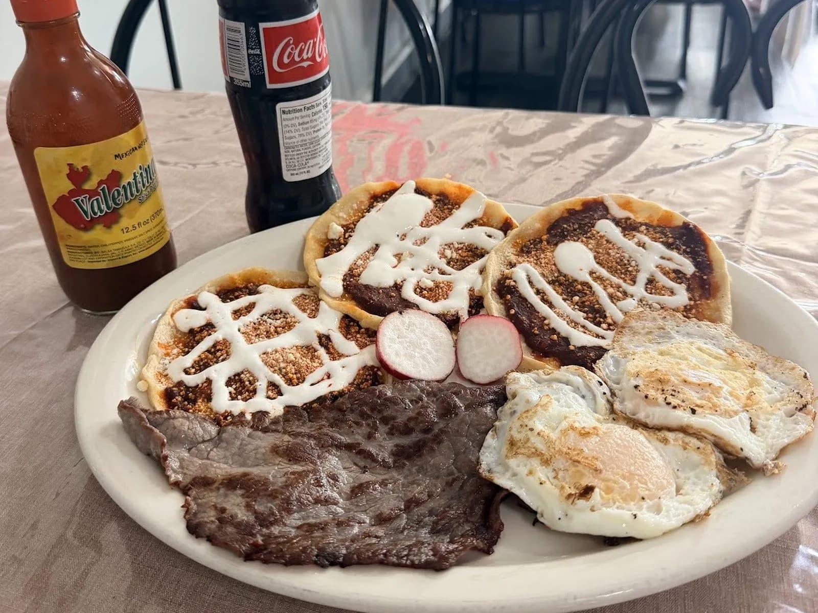 Sopes, grilled steak and fried eggs on a table at El Pilón